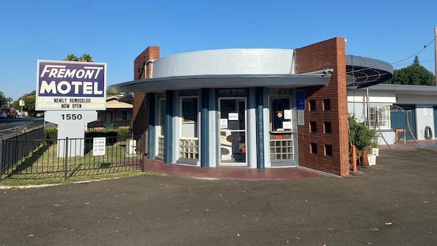 Un motel con un letrero que indica que fue remodelado recientemente y que ya está abierto.