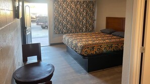 Un dormitorio con cama, una silla, una cortina y una puerta.