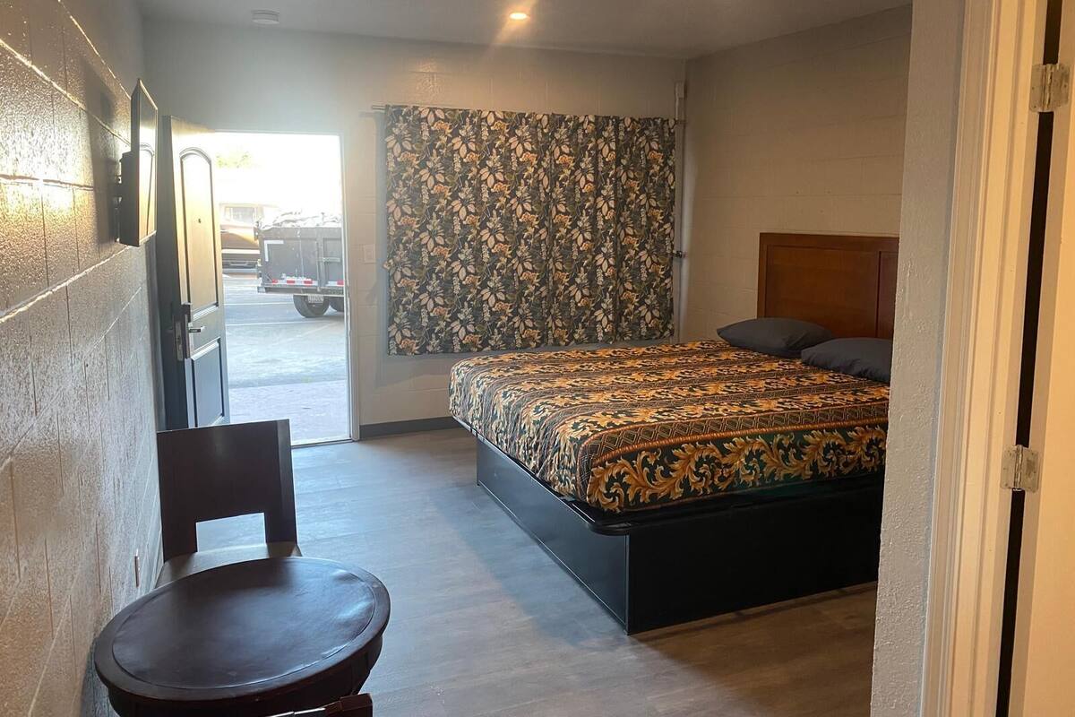 A bedroom with a bed, a chair, a curtain, and a door.