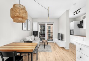 A modern kitchen with white cabinets, a wooden dining table, and a black chair. - Rakowicka Homely Studio (Kraków)
