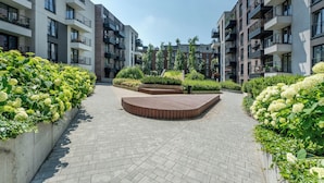 Een modern appartementencomplex met een centrale binnentuin, balkons en weelderige begroeiing.