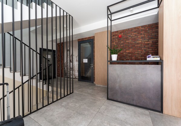 Ein moderner Empfangsbereich mit Ziegelwand, Holzpaneel und Schreibtisch mit Metallgestell.
