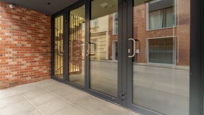 Ingresso moderno di un edificio con porte in vetro e parete in mattoni.