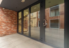 A modern building entrance with glass doors and a brick wall. - Main Station Comfort Studio (Kraków)