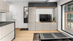 Una cucina moderna con TV integrata, mobili grigi e un piano di lavoro in legno.