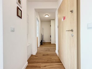 A hallway with wooden flooring, white walls, and a door with a keyhole. - Wrocław Partynice Cosy Apartment (Wrocław)