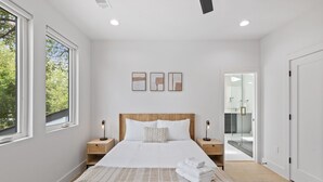Un dormitorio moderno con una cama grande, mesitas de noche y vistas al baño.