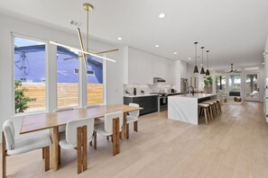 Eine moderne Küche mit weißen Schränken, einem Holztisch und Pendelleuchten.