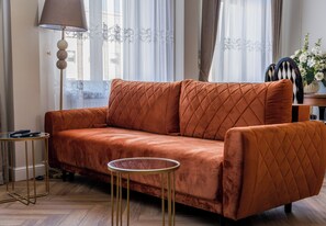 Ein Zimmer mit einer Couch, einer Lampe, einem runden Tisch und einem Stuhl.