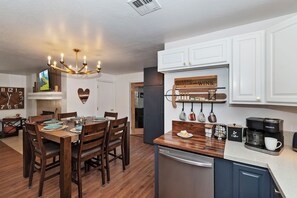A modern kitchen with a wooden dining table, a coffee station, and a refrigerator. - Home in Big Bear Lake. Walk to Snow Summit, new spa, arcade, fun yard, fire pit (Big Bear Lake)