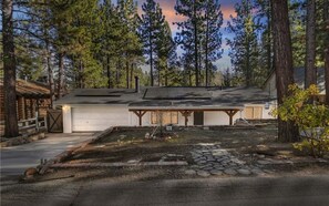 Eine Hütte mit Garage, umgeben von Bäumen, mit einem steinernen Weg zum Eingang.