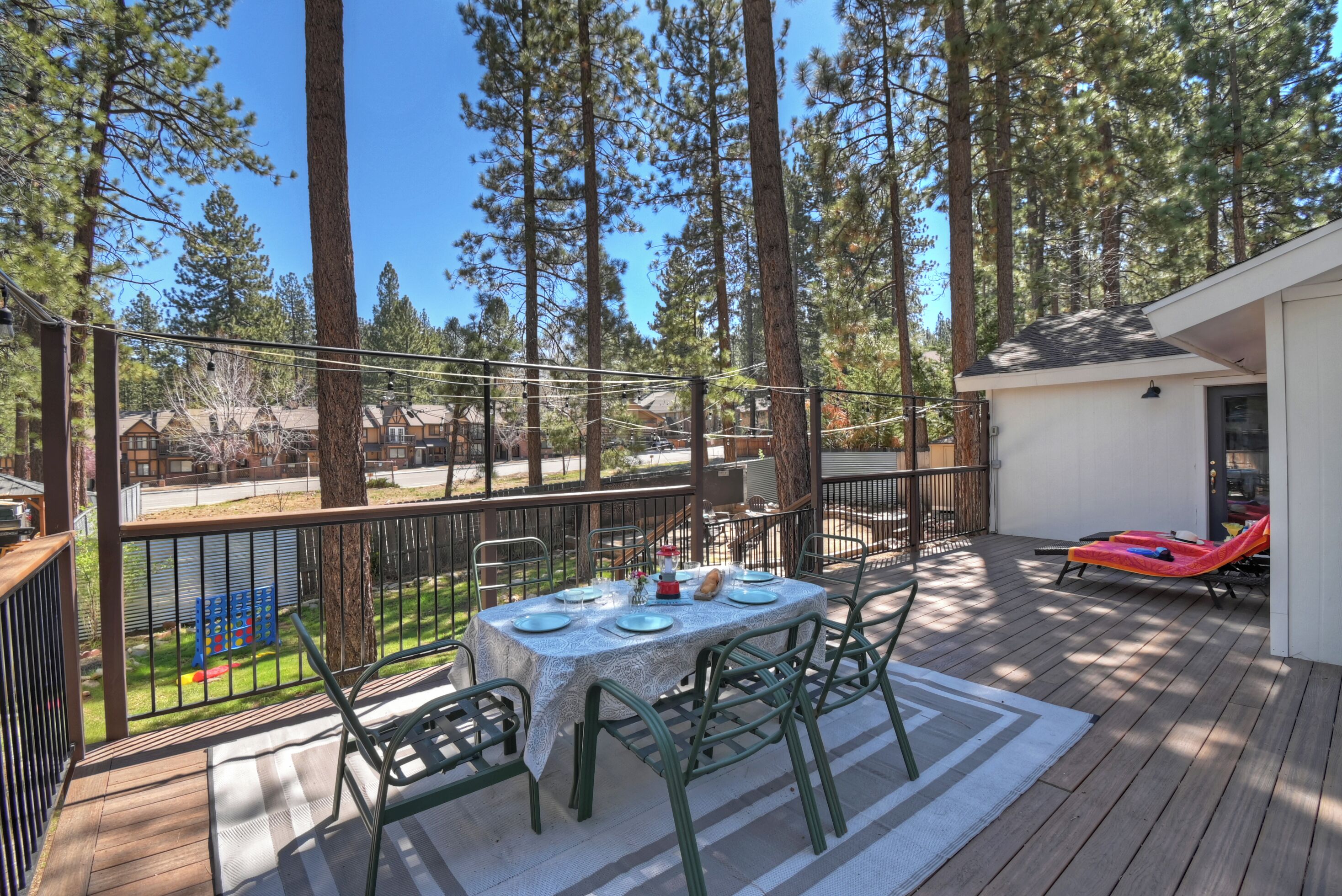 A deck with a table set for dining, surrounded by chairs, and overlooking a forested area.