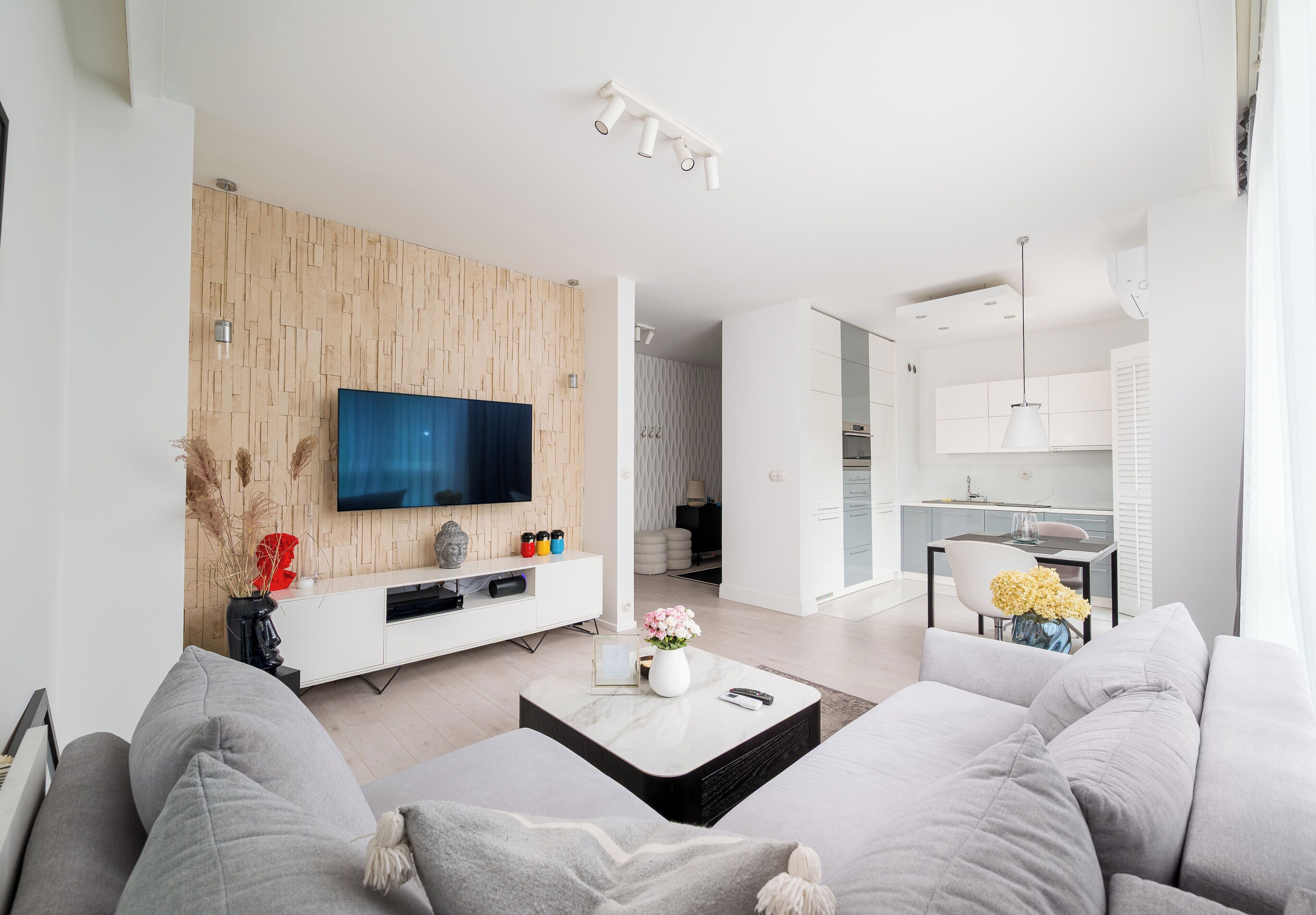 Un soggiorno moderno con una TV a schermo piatto, divani grigi, un tavolino da caffè e una parete decorata in legno.