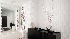 Ein modernes Zimmer mit einer schwarzen Konsole, einer weißen Wand mit Struktur und einem Spiegel mit Beleuchtung.