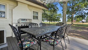 Eine Terrasse im Freien mit Grill, Tisch und Stühlen.