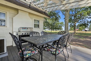 An outdoor patio with a grill, a table, and chairs.