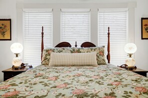A bed with a floral bedspread, wooden headboard, and two bedside lamps.