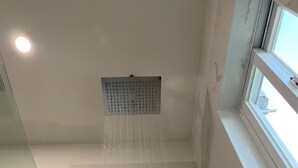 Une salle de bain moderne avec une douche, une fenêtre et un sol en marbre.