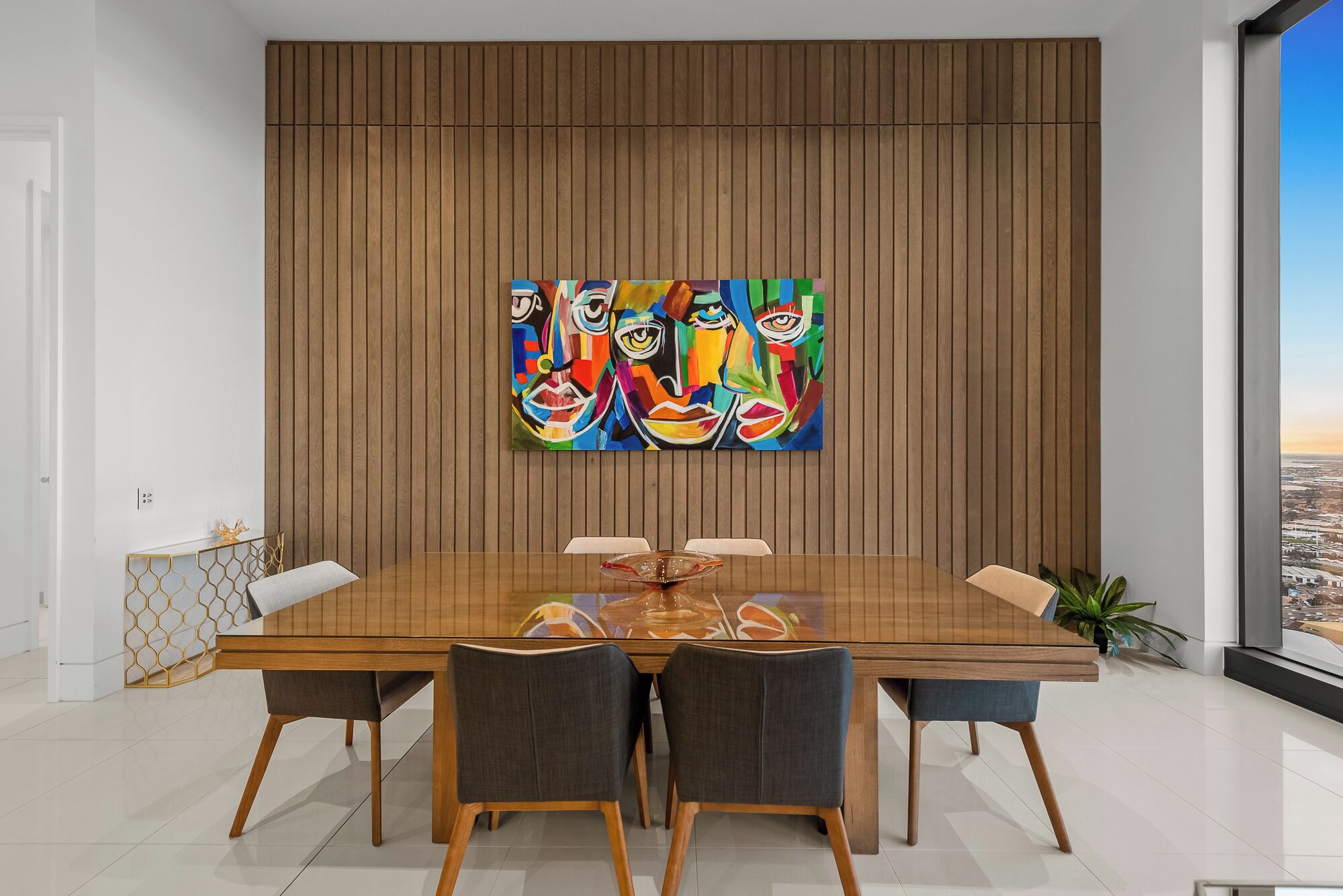Een moderne eetkamer met een wand van houtpanelen, een grote tafel en vier stoelen.