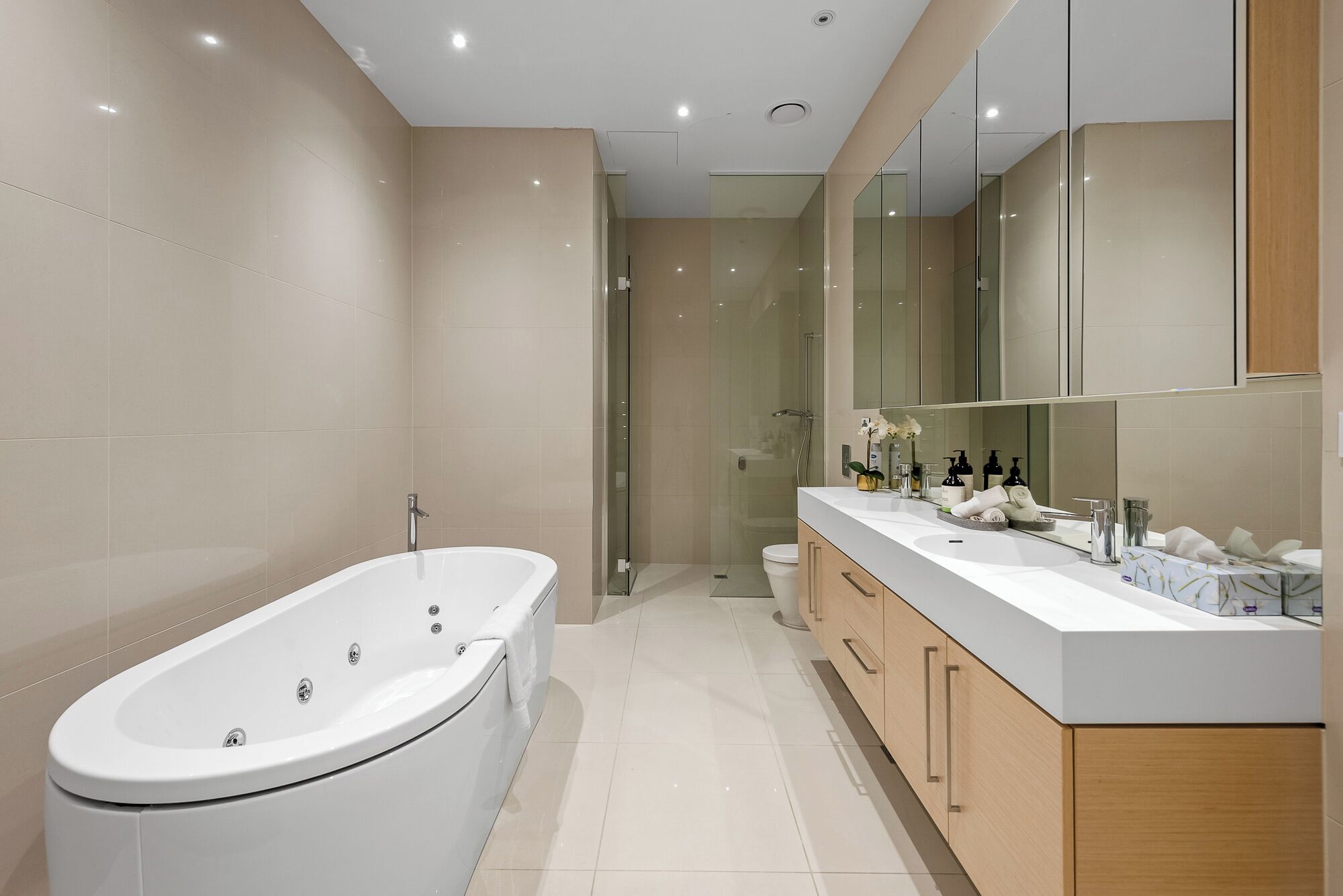 A modern bathroom with a freestanding bathtub, a glass-enclosed shower, and a vanity with a large mirror.