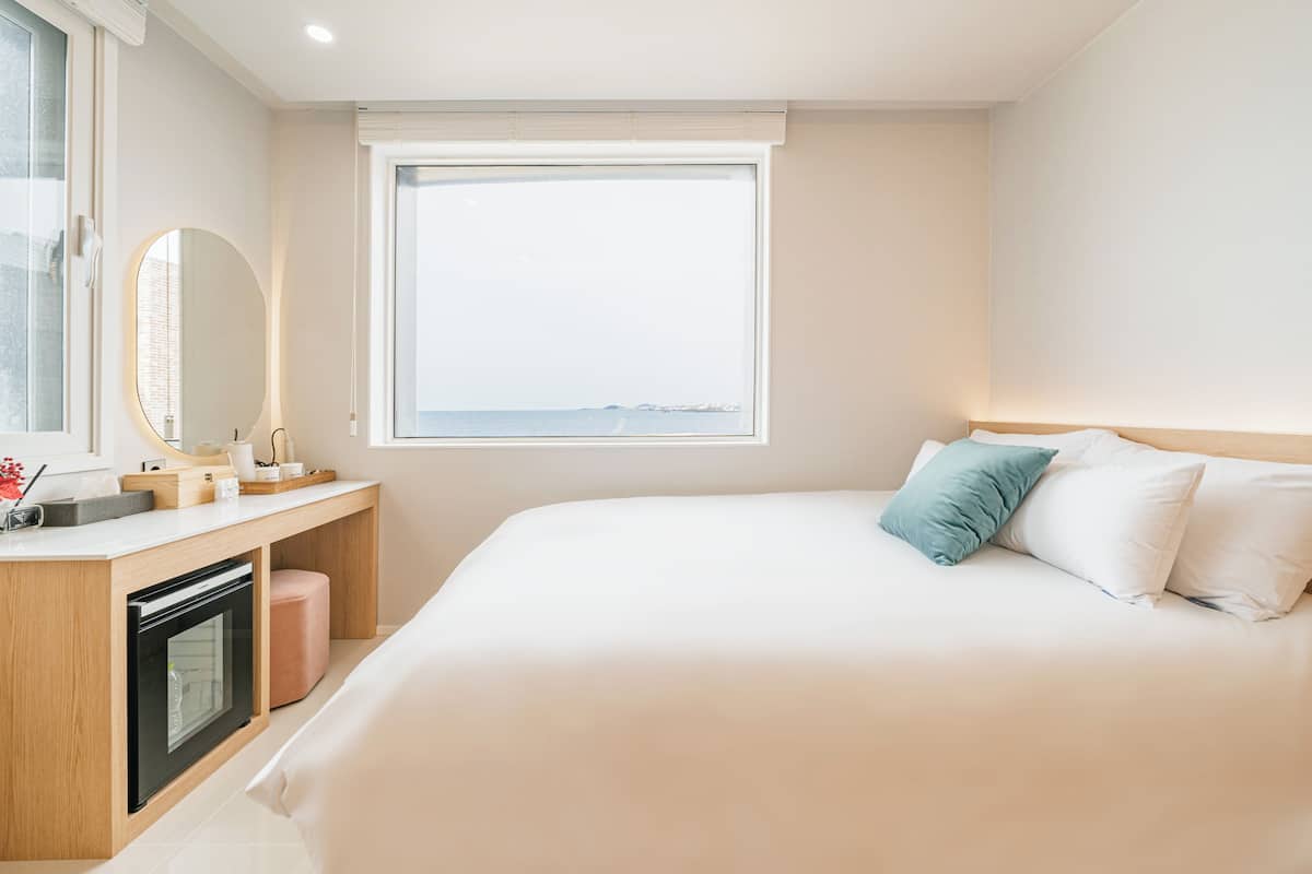 Une chambre d’hôtel comprenant un lit, une table de chevet avec un miroir, une fenêtre donnant sur un paysage agréable et un four encastré.