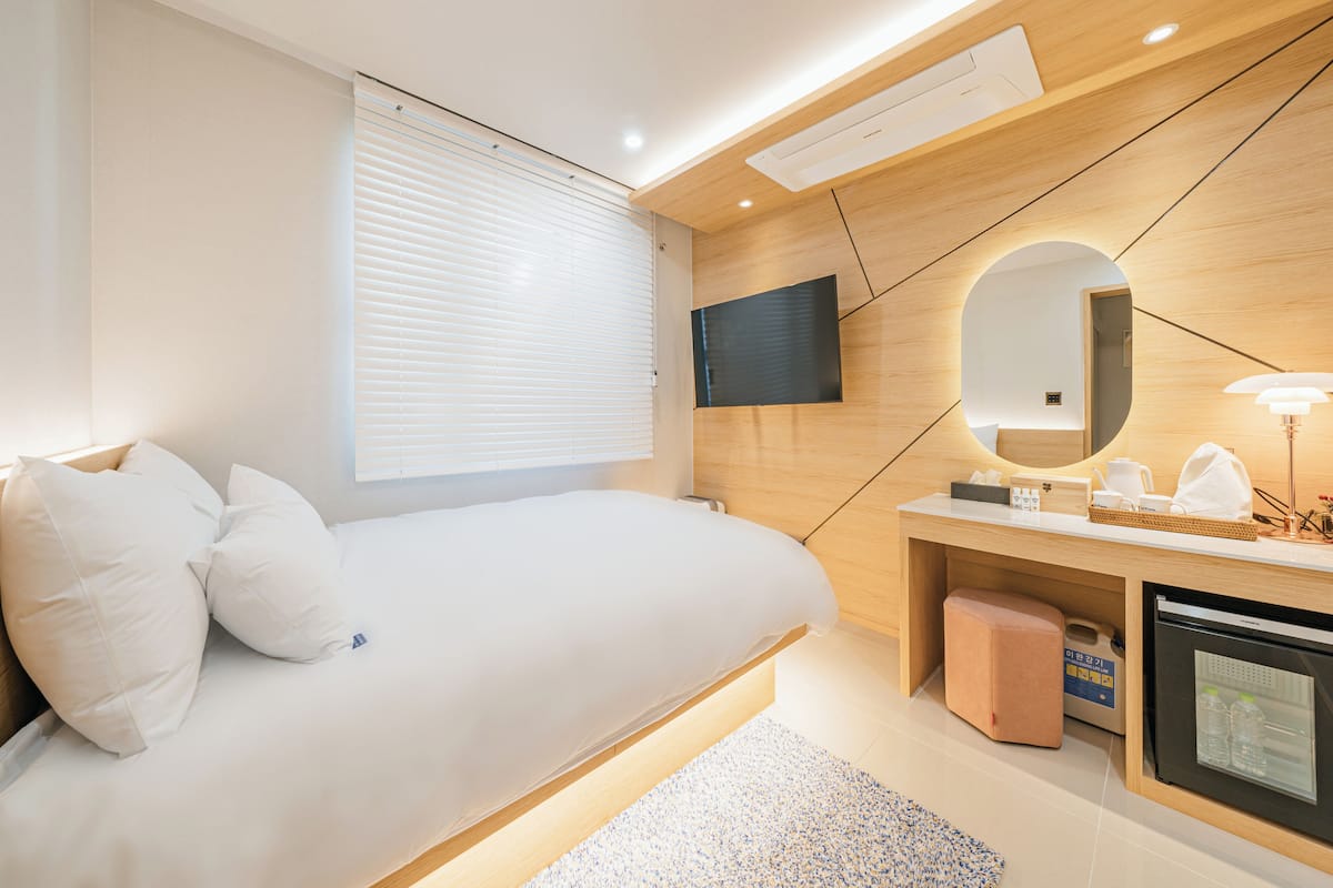 Une chambre moderne comprenant un lit, une table de chevet, un miroir et un téléviseur intégré.