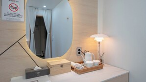 Un baño moderno con un espejo grande, un perchero para toallas, un lavamanos y una tocador con artículos de aseo.