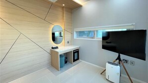 Un baño moderno con tocador, espejo, televisión y un calentador portátil.