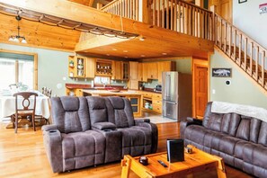 Ein großzügiger Wohnbereich mit Ledersofas, einem Holztisch und einer Küche im Hintergrund.