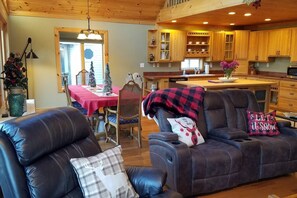 Ein gemütliches Wohnzimmer mit einer Ledersofa, ein Essbereich mit einem roten Tisch und eine Küche mit Holzschränken.