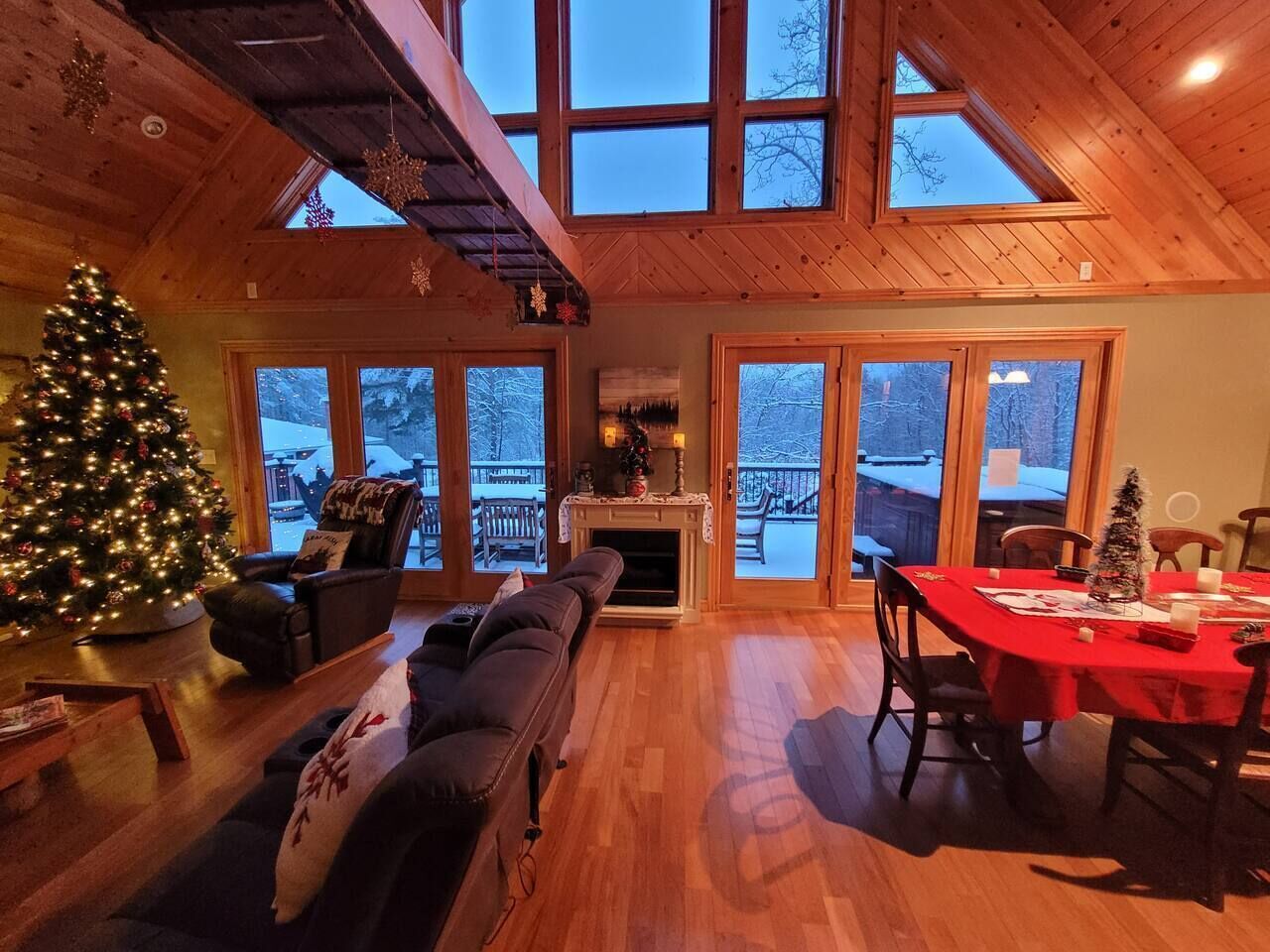 L’intérieur chaleureux d’un chalet avec une cheminée, un sapin de Noël et un coin repas.