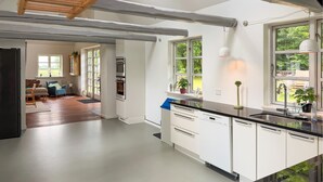 A modern kitchen with white cabinetry, a black countertop, and a window overlooking a garden. - 3 bedroom lovely home in Nexø (Nexø)