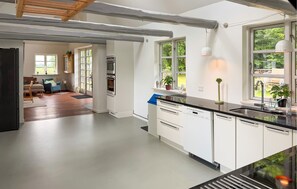 A modern kitchen with white cabinetry, a black countertop, and a window overlooking a garden. - 3 bedroom lovely home in Nexø (Nexø)
