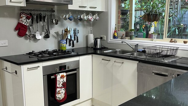 Een moderne keuken met witte kastjes, een zwart aanrecht en een rvs afzuigkap.