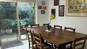 Een eetruimte met een houten tafel, stoelen en een potplant.