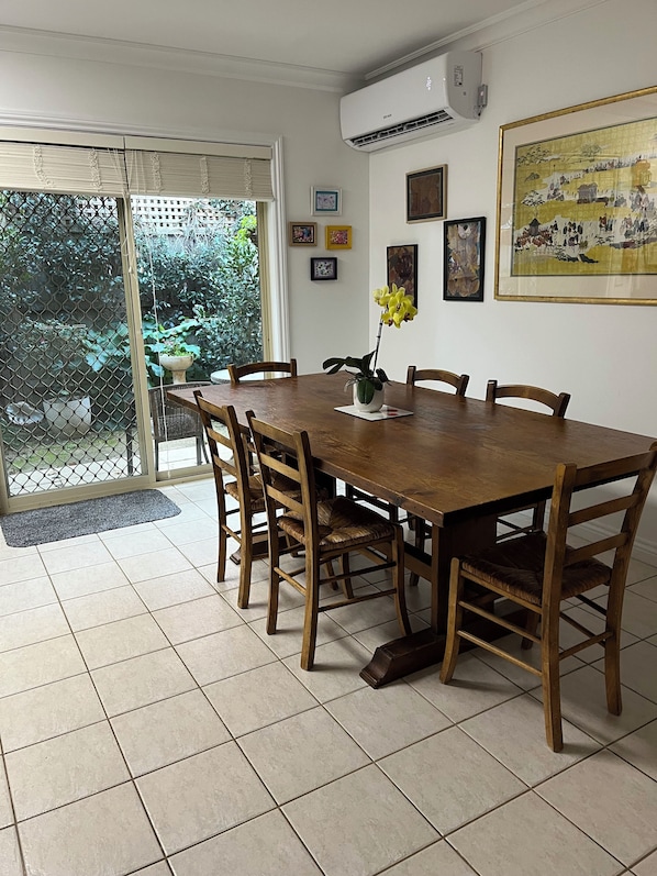 A dining area with a wooden table, chairs, and a potted plant. - Light bright and airy, garden outlook from every window, quiet location (Glen Iris)