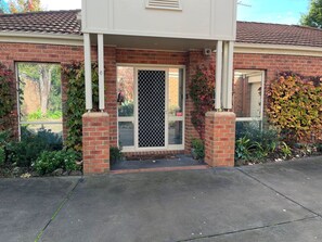 A residential building with a brick facade, a front door with a security screen, and a small porch area. - Light bright and airy, garden outlook from every window, quiet location (Glen Iris)
