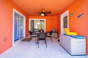 A room with a ceiling fan, a dining table with chairs, a white cabinet, and a glass door leading outside. - Dolphin Villa: Pool House Near Disney, Universal, more. Family Fun, Private Pool (Davenport)