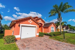 A residential house with a white garage door, a brick driveway, and a well-maintained lawn. - Dolphin Villa: Pool House Near Disney, Universal, more. Family Fun, Private Pool (Davenport)