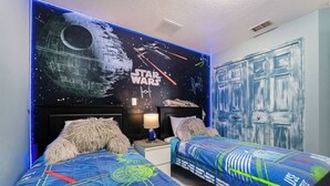 Et soveværelse med Star Wars-tema, herunder et vægmaleri og sengetøj.
