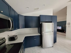 A modern kitchen with dark blue cabinets, stainless steel appliances, and a white countertop. - Dolphin Villa: Pool House Near Disney, Universal, more. Family Fun, Private Pool (Davenport)