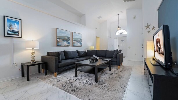 En moderne stue med sofa, sofabord, fjernsyn og kunst på væggene.