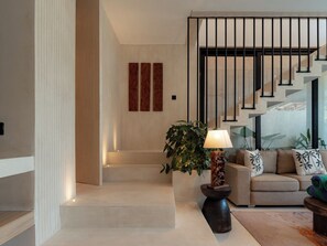 A modern interior with a staircase, a sofa with patterned cushions, and a lamp. - Villa Marma (Bali)