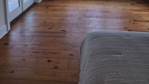 Une pièce dotée d’un plancher en bois, d’une grande fenêtre donnant sur la mer et d’un plafond agrémenté d’une touche de bleu.