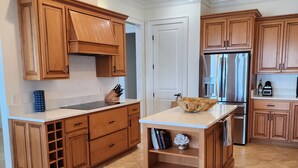 Une cuisine avec des meubles en bois, un réfrigérateur en acier inoxydable et un plan de travail en marbre.