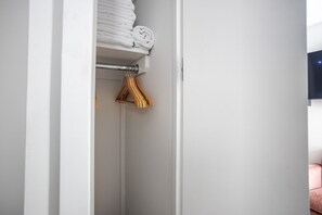 A white closet with neatly folded white towels and a wooden towel rack. - Blueground | SoHo, view, nr Washington Square Park (New York)