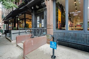 A building with a storefront, a wheelchair accessibility sign, and a fire alarm button. - Blueground | SoHo, view, nr Washington Square Park (New York)