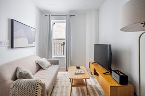 Ein modernes Wohnzimmer mit einer Couch, einem Couchtisch, einem Fernseher und einer Lampe.