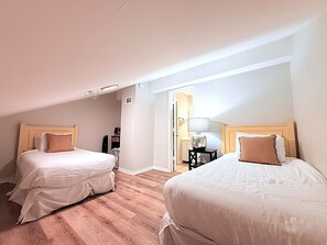 A hotel room with two beds, a wooden headboard, a bedside table with a lamp, and a door leading to another room. - Beach Front Paradise/Unobstructed Gulf View From Private Balcony/Pool (Destin)