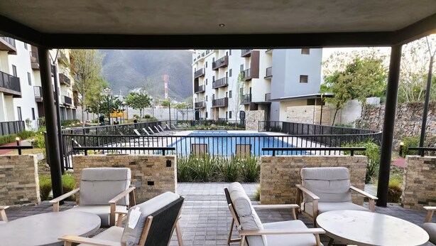 Un espace extérieur aménagé, abrité et doté d’une piscine, de murs en pierre et d’une vue sur des immeubles d’habitation.